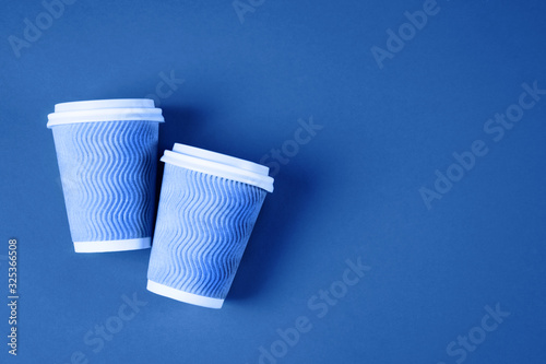 Two paper coffee cups on blue background.