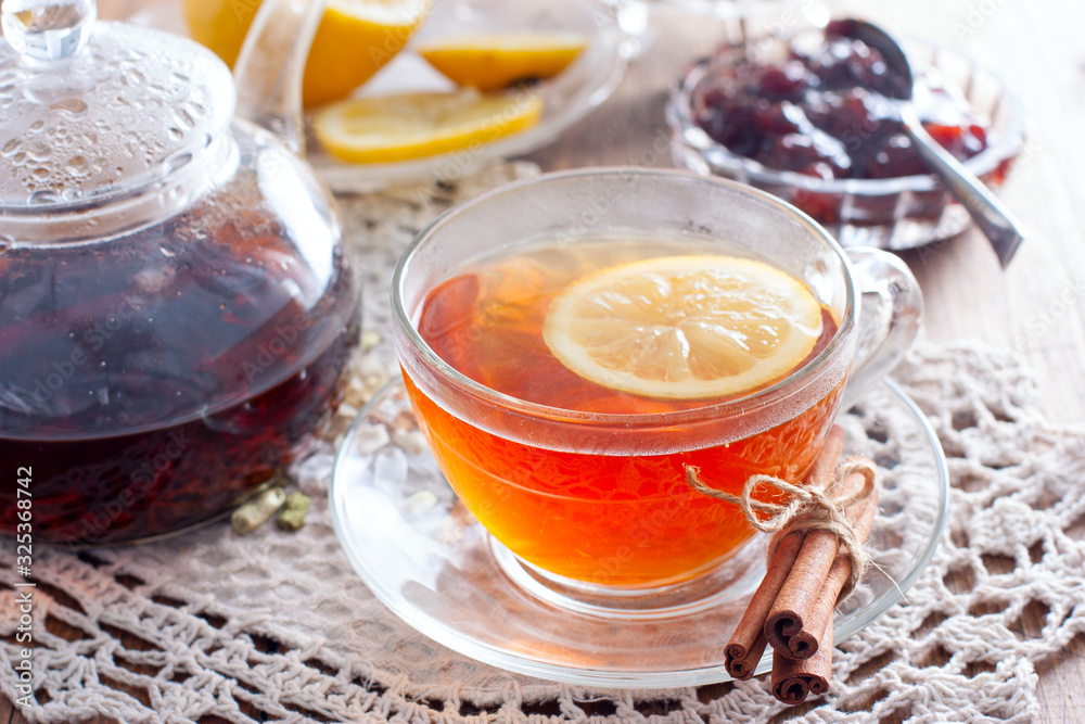 Black tea with cinnamon and lemon in a glass cup on a wooden table, horizontal Black tea with cinnamon and lemon in a glass cup on a wooden table, horizontal