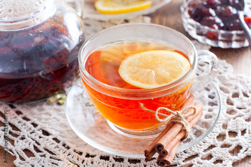 Black tea with cinnamon and lemon in a glass cup on a wooden table, horizontal