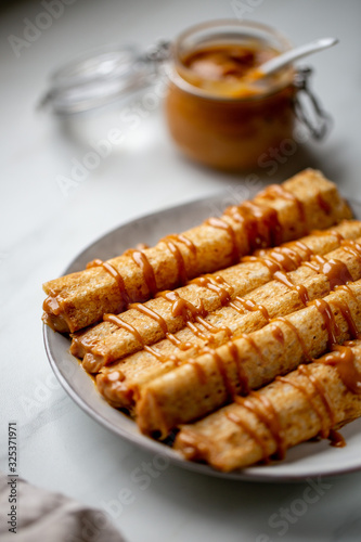 french crepe filled with caramel fudge and decorated with chocolate fudge, berries castor sugar and mint leaves on marble background with copy space