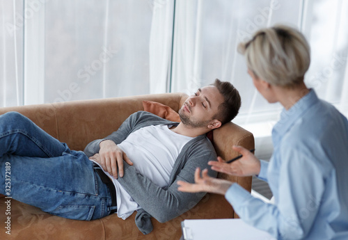 Patient Talking With Psychologist Lying On Couch In Office