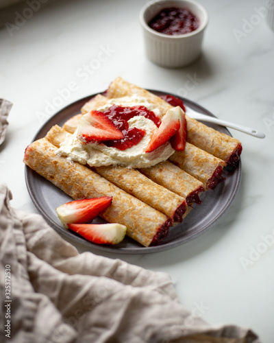 french crepe filled with caramel fudge and decorated with chocolate fudge, berries castor sugar and mint leaves on marble background with copy space
