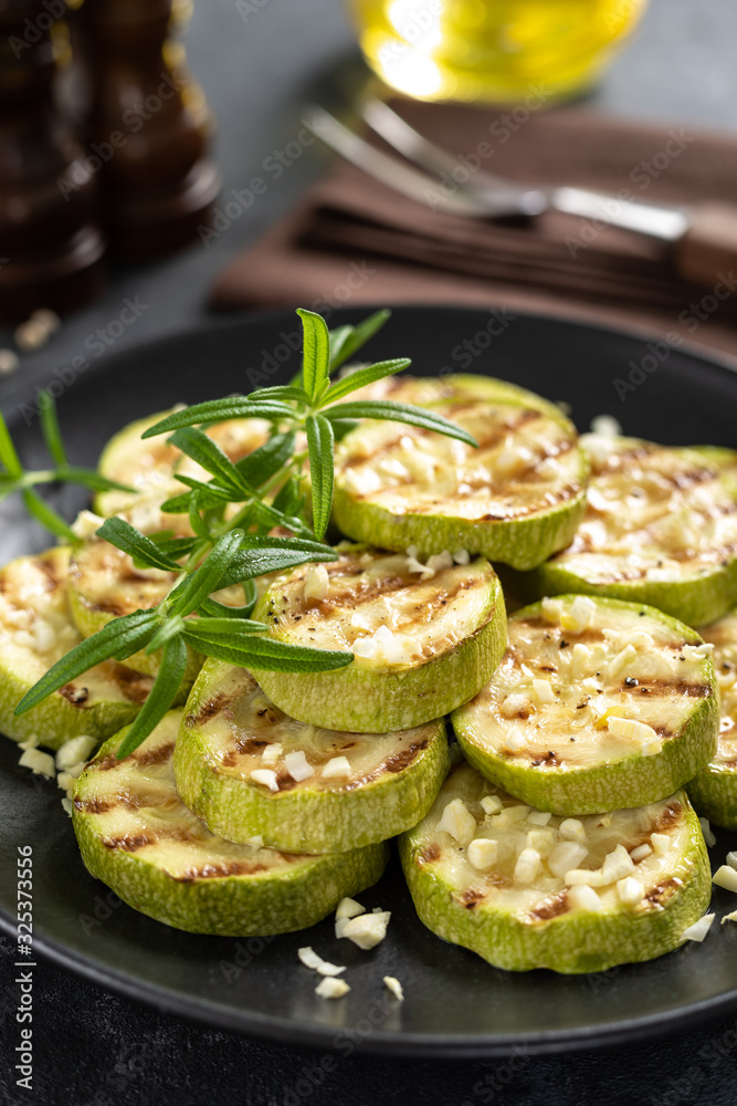 Grilled zucchini, courgette with garlic and rosemary on plate Grilled zucchini, courgette with garlic and rosemary on plate