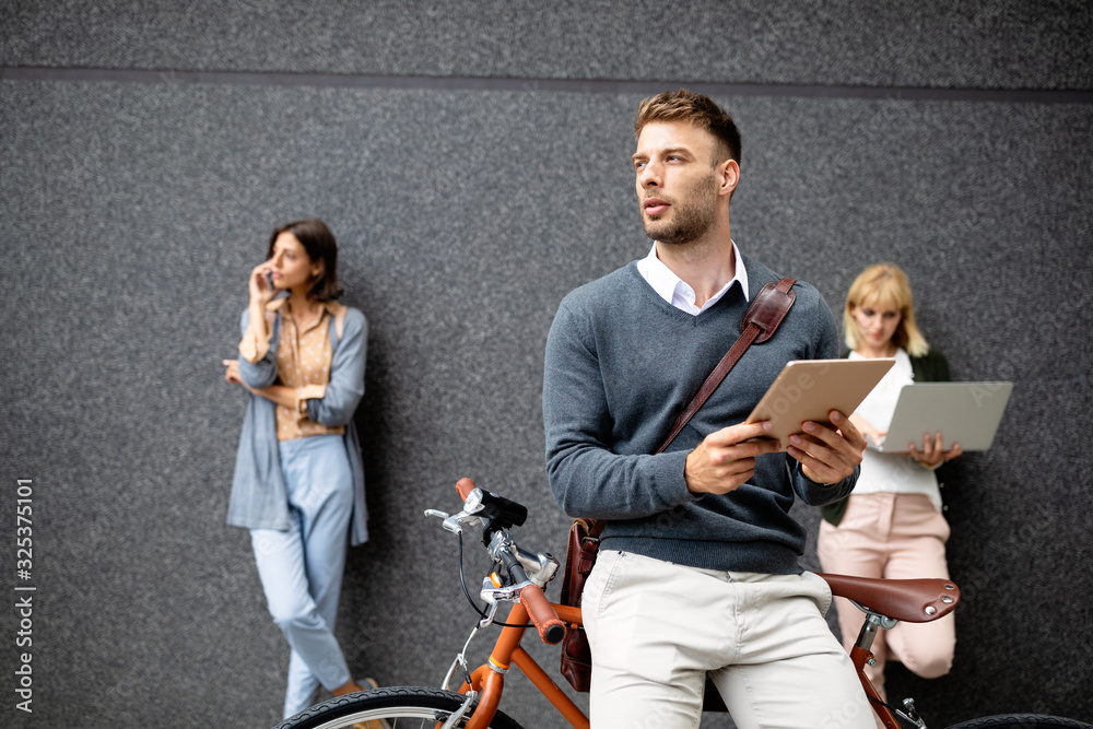 Group of happy young business people holding different digital devices outdoor.