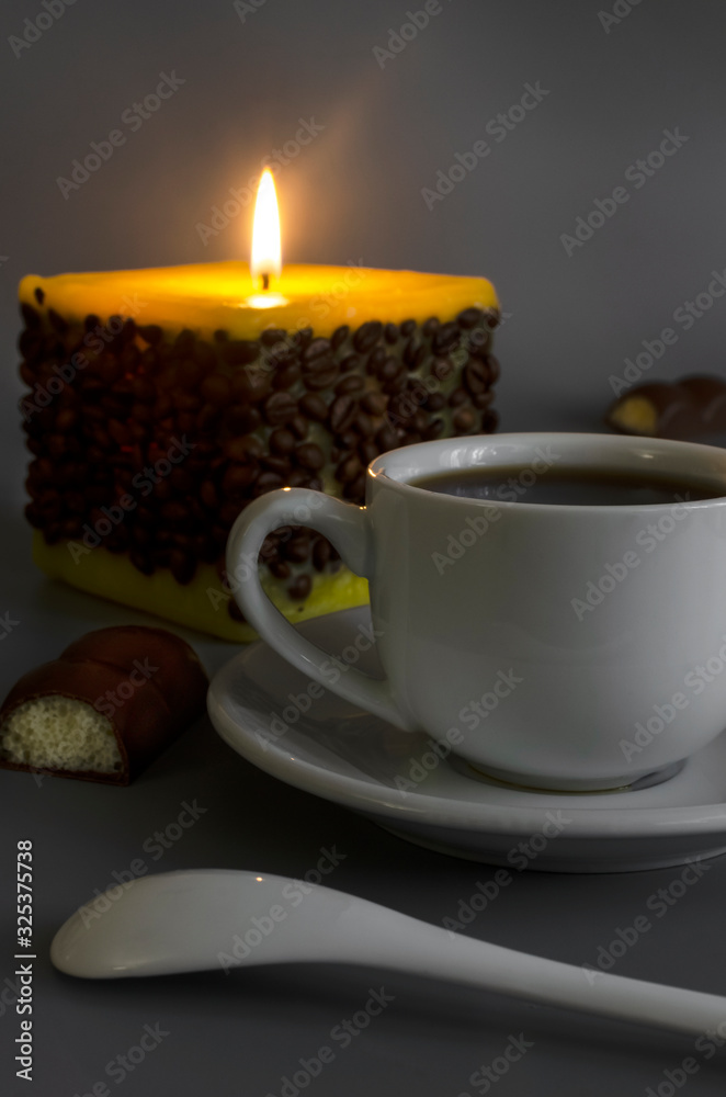 Cup of coffee on a background of a burning candle Cup of coffee on a background of a burning candle