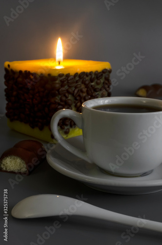 Cup of coffee on a background of a burning candle