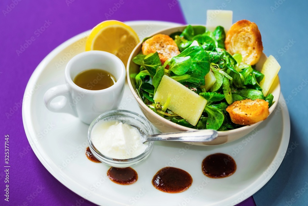 Green leaf valerianella salad with parmesan and bread, yogurt,oil and lemon on plate. Green leaf valerianella salad with parmesan and bread, yogurt,oil and lemon on plate.