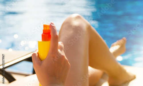 Woman applying sunblock cream on her legs.