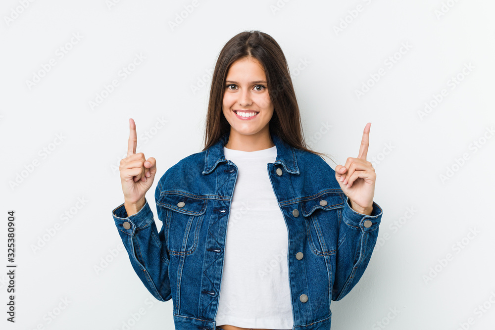 Young cute woman indicates with both fore fingers up showing a blank space. Young cute woman indicates with both fore fingers up showing a blank space.
