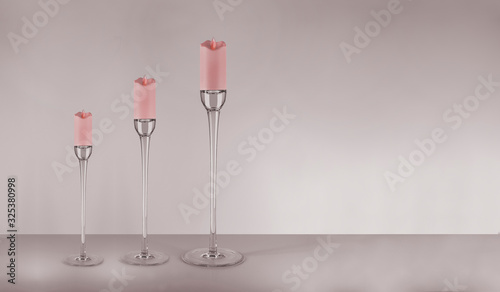 Modern style glass pastel coloured candlesticks with red candles and flames on the floor. Home decoration. Interior objects with clean red background.