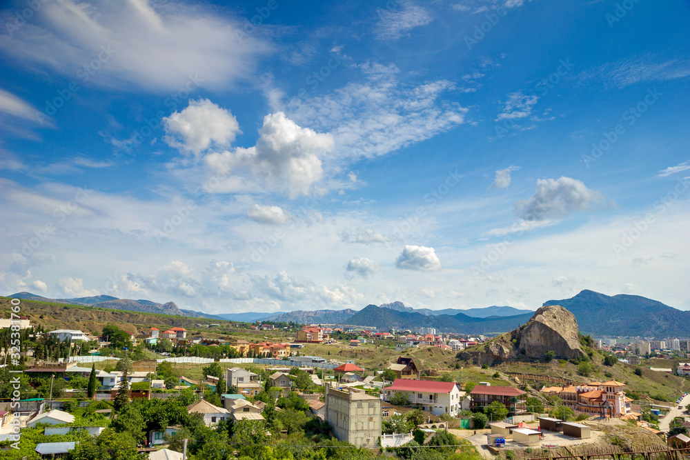 Picturesque view of a small town at the foot of the mountains in a sunny day. Beautiful mountain landscape. 