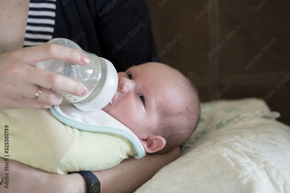 Little infant baby lying on mothers hand drinking milk from bottle. Baby food. Mom and child. Little infant baby lying on mothers hand drinking milk from bottle. Baby food. Mom and child.