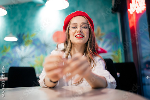 Girl eats lolly pop candy on stick in cafeteria in France, young woman red beret and glasses