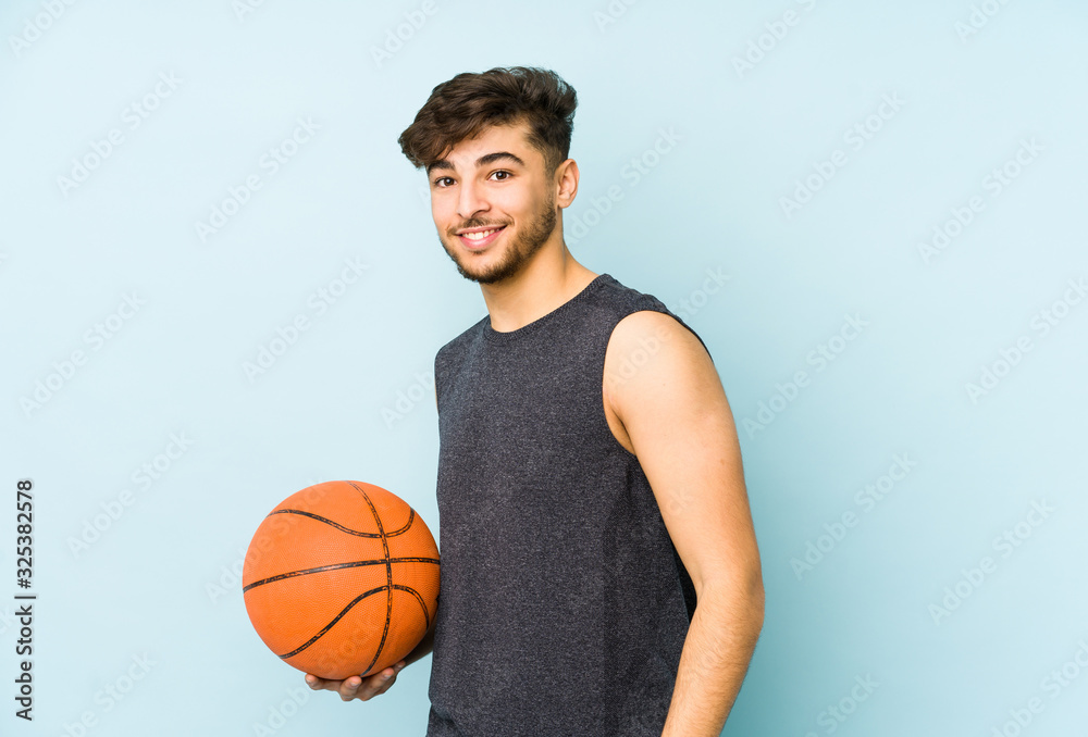 Young arabian man playing basket isolated looks aside smiling, cheerful and pleasant.