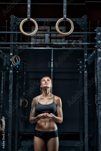 Fotografie Slender and fit young athlete getting ready for exercise on gymnastic rings