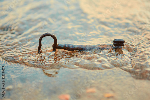 The old vintage iron key washed ashore in waves.  Who will find him first and he will become rich and happy