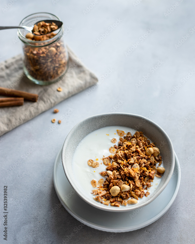 homemade granola with nuts, cinnamon and natural yogurt in a bowl. Healthy and organic nutrition concept. gray concrete background. vertical image. copy space homemade granola with nuts, cinnamon and natural yogurt in a bowl. Healthy and organic nutrition concept. gray concrete background. vertical image. copy space