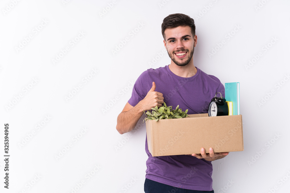 Young caucasian man moving a new home isolated smiling and raising thumb up Young caucasian man moving a new home isolated smiling and raising thumb up