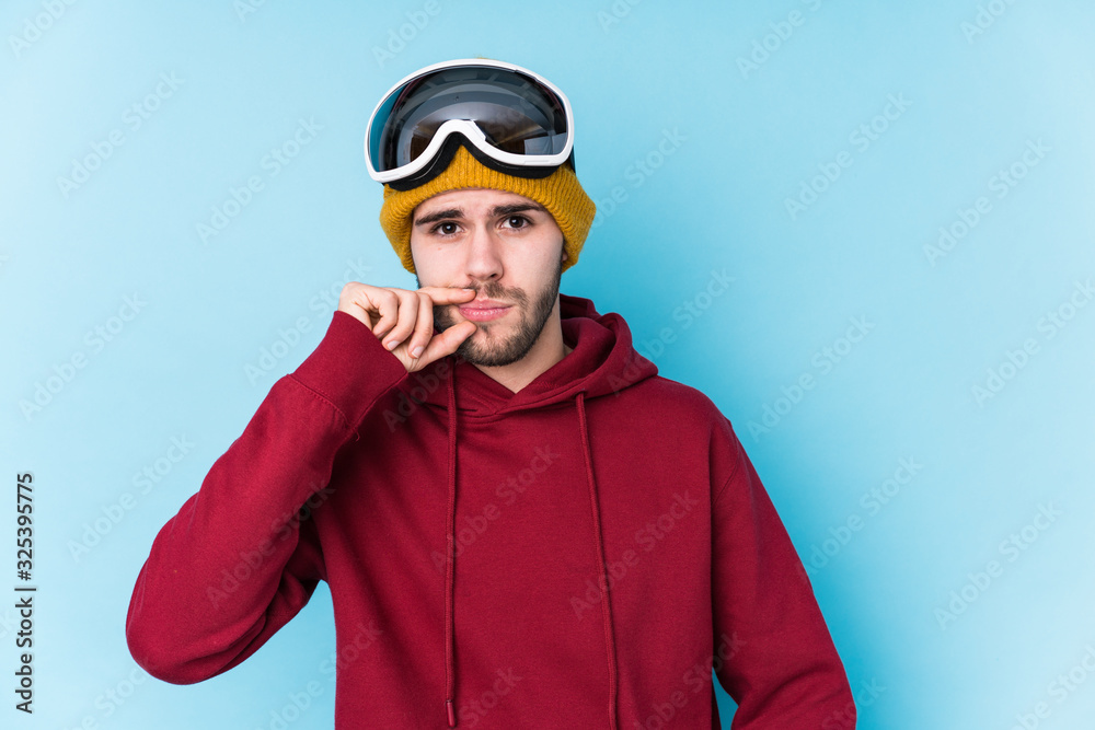 Young caucasian man wearing a ski clothes isolated with fingers on lips keeping a secret.