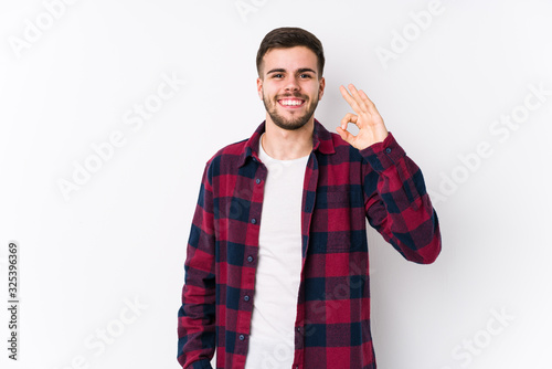 Tableau sur toile Young caucasian man posing in a white background isolated cheerful and confident showing ok gesture