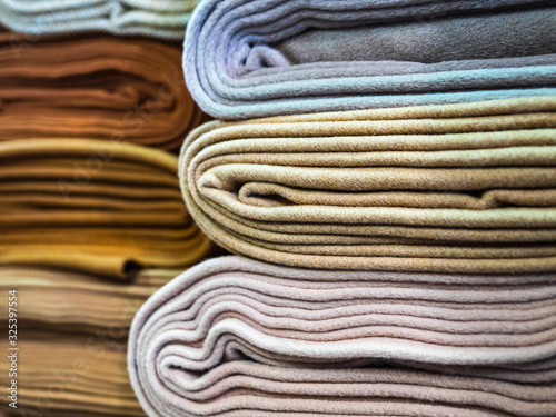 Rolls of warm dense fabrics in pastel colors, close-up. Trendy collection of monochrome fabrics, a new trend. Beautiful natural fabric lies in layers on store shelves for sale