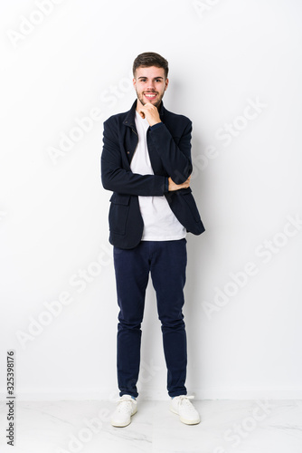 Full body young caucasian man isolated smiling happy and confident, touching chin with hand.