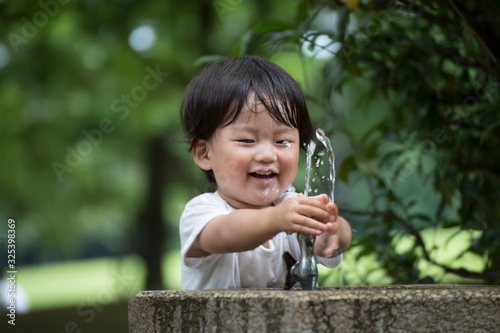 公園で水遊びをする無邪気で元気な男の子.