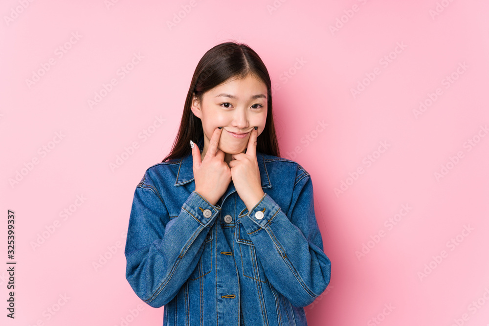 Young chinese woman posing in a pink background isolated doubting between two options. Young chinese woman posing in a pink background isolated doubting between two options.