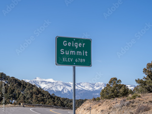 Road elevation sign on Geiger Grade with snow capped mountains and a blue sky background. 