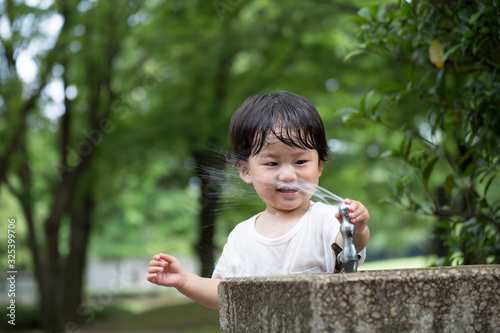 公園で水遊びをする無邪気で元気な男の子.