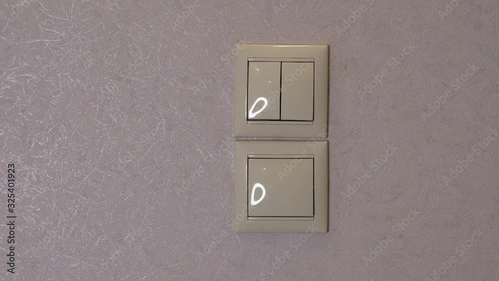 Light is Off - female hand switch off a button on a light-grey wall, front view Light is Off - female hand switch off a button on a light-grey wall, front view