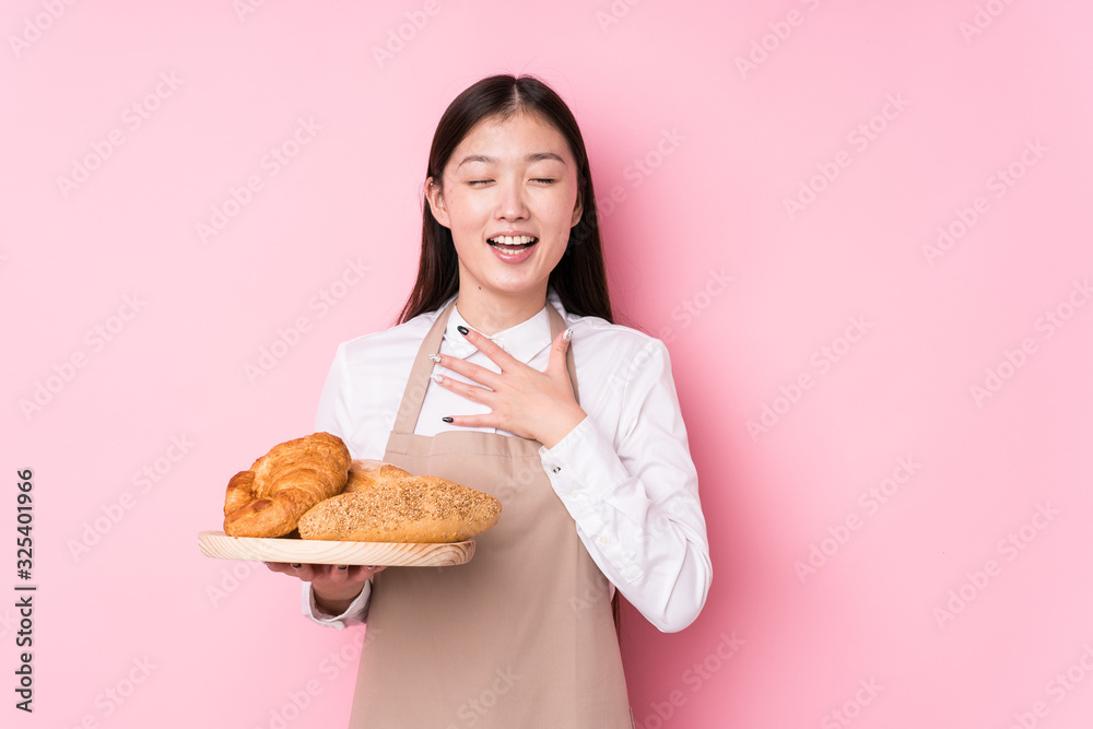 Young chinese baker woman isolated laughs out loudly keeping hand on chest. Young chinese baker woman isolated laughs out loudly keeping hand on chest.
