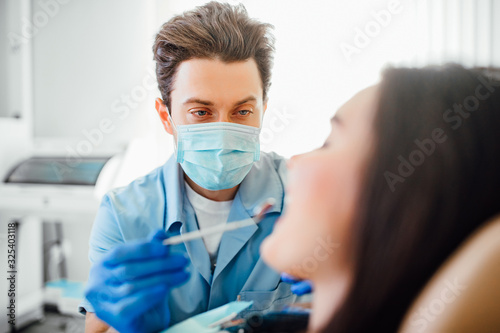 Professional dentist man in mask working with patient in modern clinic.
