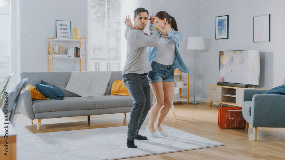Happy Beautiful Couple is Having Fun and Actively Dancing in their Cozy Living Room at Home. They Smile and Laugh. Happy Beautiful Couple is Having Fun and Actively Dancing in their Cozy Living Room at Home. They Smile and Laugh.