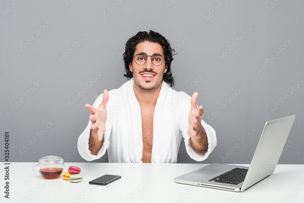 Young handsome man working after a shower feels confident giving a hug to the camera. Young handsome man working after a shower feels confident giving a hug to the camera.
