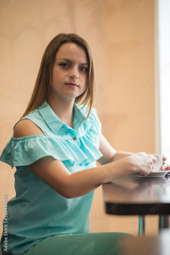 Beautiful young girl with her hair in a cafe is drinking coffee. Beautiful young girl with her hair in a cafe is drinking coffee.
