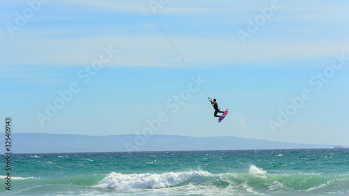 kite surfer flying while sailing in a paradise spot to practice the sport