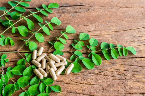 Moringa leaves with Moringa capsules on old wood. Healthy herbs. photo