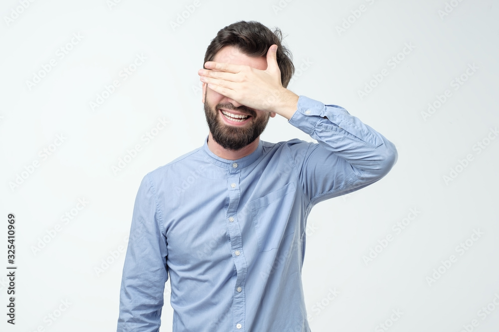 Fototapeta premium Young happy hispanic man screaming and covering eyes with hands