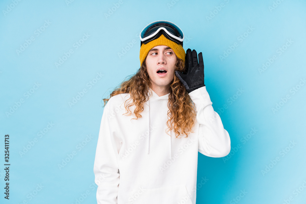 Young caucasian man wearing a ski clothes isolated trying to listening a gossip. Young caucasian man wearing a ski clothes isolated trying to listening a gossip.