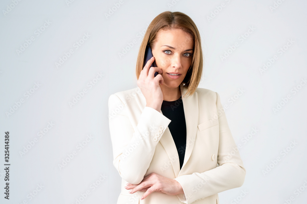 Close-up of middle aged businesswoman using her mobile phone while standing at isolated white background Close-up of middle aged businesswoman using her mobile phone while standing at isolated white background