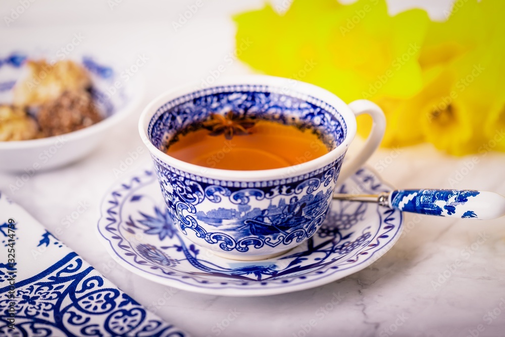 A cup of tea with anise star. White and blue dishes and yellow daffodils A cup of tea with anise star. White and blue dishes and yellow daffodils