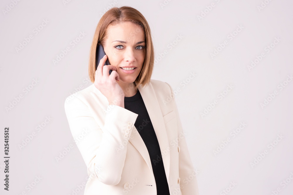 Close-up of middle aged businesswoman using her mobile phone while standing at isolated white background Close-up of middle aged businesswoman using her mobile phone while standing at isolated white background