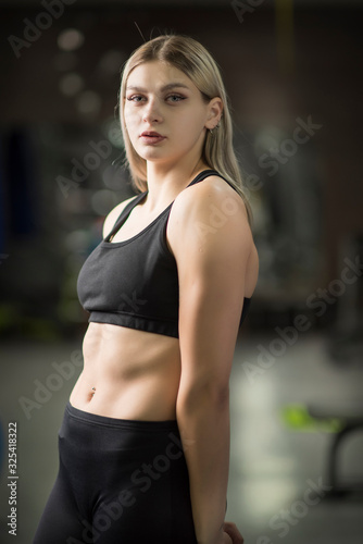 Portrait of a girl in a fitness hall in the sports form with a blurred background.