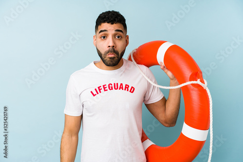 Young latin lifeguard man isolated shrugs shoulders and open eyes confused.