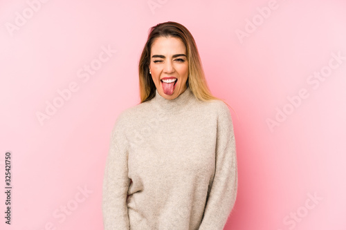 Middle age woman over isolated background funny and friendly sticking out tongue.