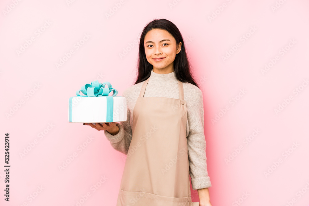 Young chinese woman holding a cake isolated person pointing by hand to a shirt copy space, proud and confident Young chinese woman holding a cake isolated person pointing by hand to a shirt copy space, proud and confident