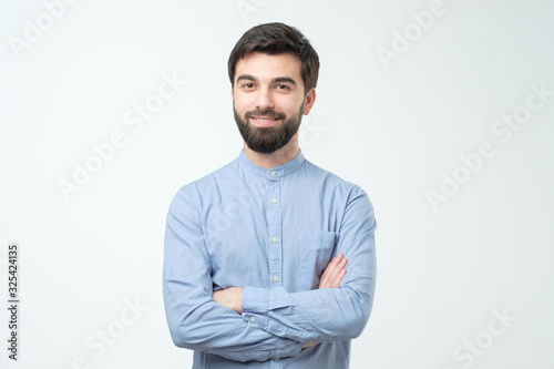 Hispanic young man standing with his arm crossed over white background © Viktor Koldunov