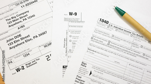 IRS 1040, W-2 and W-9 tax return form and Green Pen. Wage and tax statement concept