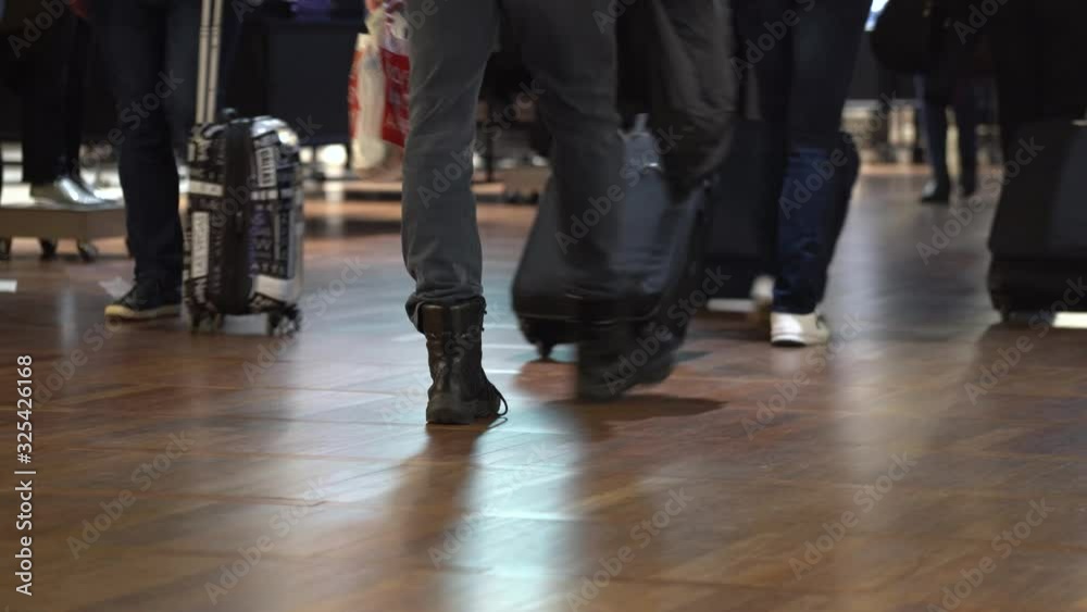 tripod shot group of people with carry on luggage walk in terminal